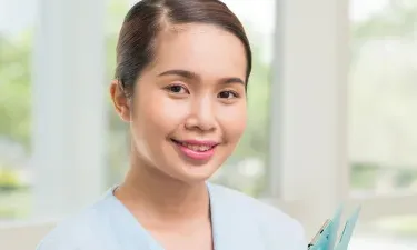 Medical Assistant Holding Clipboard Smiling in Hallway