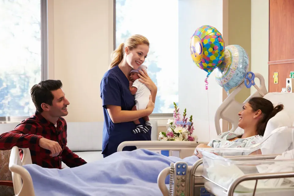分娩护士抱着婴儿，微笑着迎接新父母